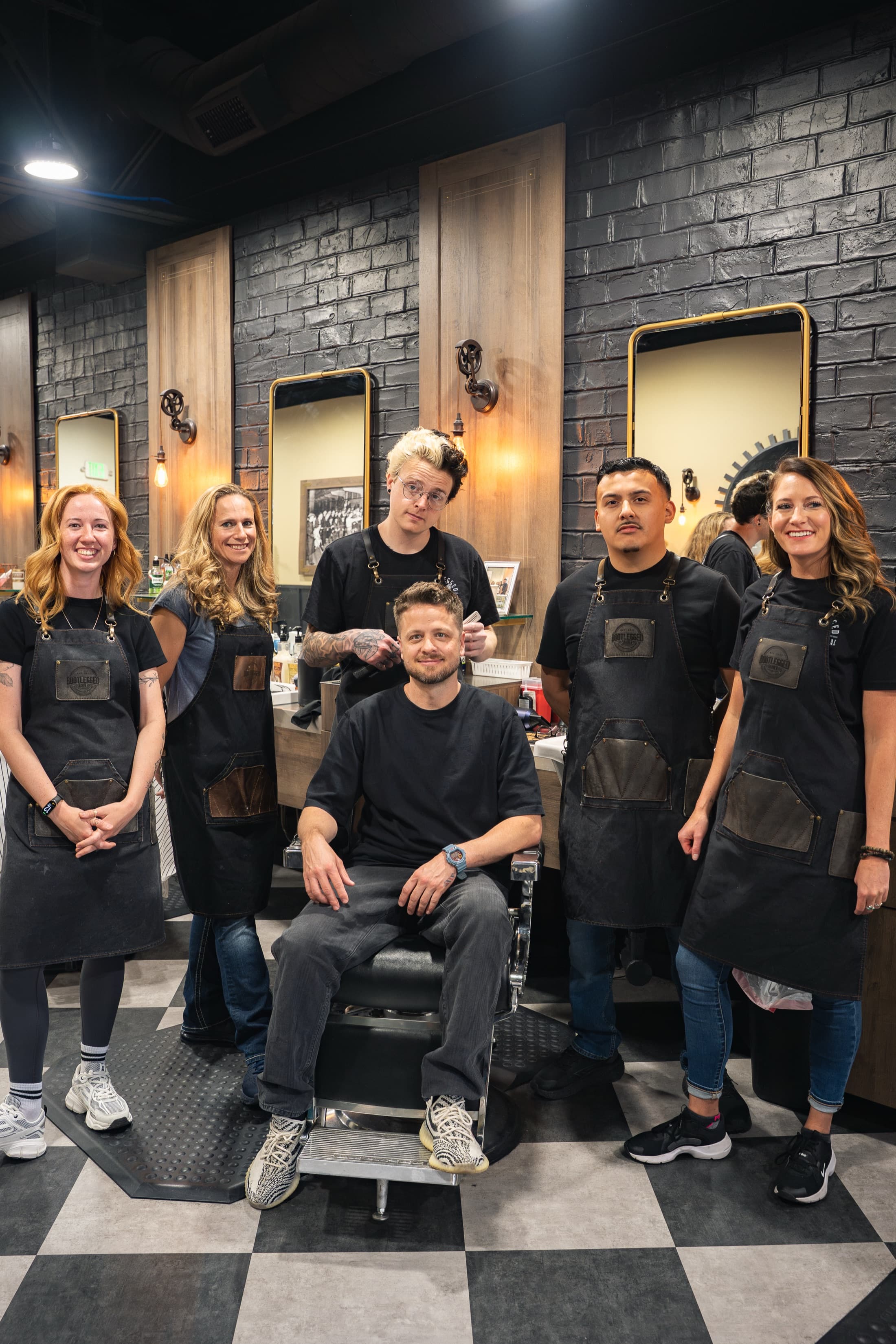 The Bootlegged Barber Sandy team in matching black tees and leather-trimmed aprons